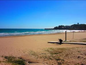 a bench sitting on a beach near the ocean at Cala Azul 304-306 Tamarit in Tamarit
