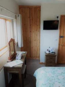 a bedroom with a bed and a desk with a mirror at Three Ways Farmhouse B&B in Stratford-upon-Avon