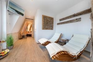 una sala de estar con sillas blancas y una escalera en Villa Strandblick 4, en Zingst