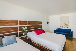 a bedroom with two beds and a blue chair at Millenium Plaza & Suites in San Luis Potosí