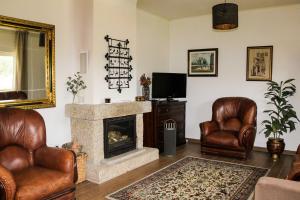 a living room with two leather chairs and a fireplace at Quinta Chão do Nabal in Belmonte