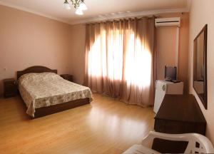 a bedroom with a bed and a large window at Hotel Kiparis in Pizunda
