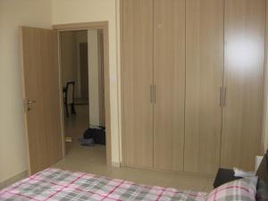 um quarto com uma cama e armários de madeira em Pyla Village Resort F110 (Apartment near Larnaca) em Pyla