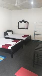 1 dormitorio con 2 camas y espejo en la pared en Friends Paradise, en Kilinochchi