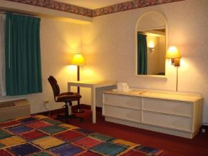 a room with a bed, chair, lamp and a mirror at O'Hare Inn & Suites in Schiller Park