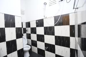 a black and white tiled bathroom with a toilet at Isuru Homestay in Ella