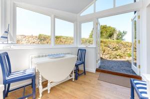 a dining room with a table and chairs and windows at Wrens Nook in St. Agnes 