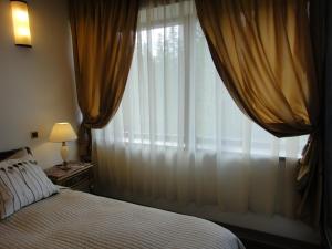 a bedroom with a bed and a window with curtains at Chambres Mountain in Poiana Brasov