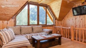a living room with a couch and a tv in a cabin at Зарінок карпат in Mykulychyn