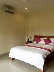 1 dormitorio con 1 cama con almohadas rosas y blancas en Bagus Homestay, en Ubud