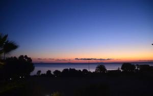 a sunset over the ocean with trees and the horizon at Rais Gerbi Appartamento in Pollina