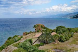 a view of the ocean from a hill with palm trees at Rais Gerbi Appartamento in Pollina