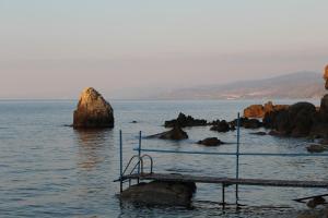 a pier in the water with rocks in the water at Rais Gerbi Appartamento in Pollina