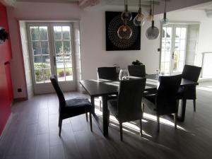 a dining room with a black table and chairs at L'Anctovillière in Anctoville