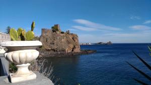 a white statue next to the water with a castle at La Castellese in Aci Castello