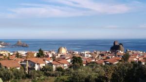 a town on a hill with the ocean in the background at La Castellese in Aci Castello