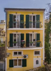 a yellow house with balconies and flowers on it at Semeli Apartment in Zakynthos Town