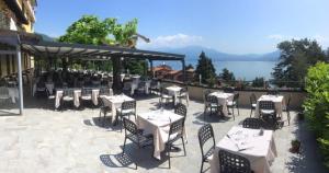 un patio con mesas y sillas y vistas al agua en Albergo Bel Soggiorno, en Oggebbio