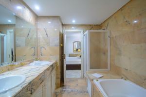 łazienka z dwiema umywalkami, wanną i prysznicem w obiekcie Apartment in White Pearl Beach w Marbelli