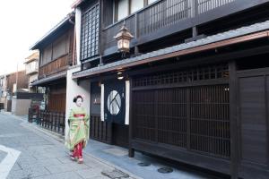 een vrouw in een groene jurk die voor een gebouw staat bij Kamishichiken Oku in Kyoto