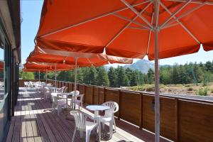 una terraza con mesas, sillas y sombrillas en Castel de Vergio, en Albertacce