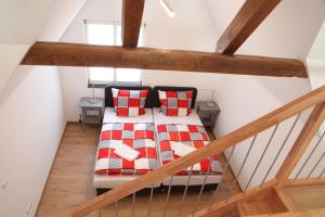 Zimmer im Dachgeschoss mit einem Bett mit roten und weißen Kissen in der Unterkunft Schwaben Apartment in Oberboihingen