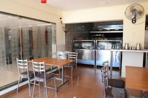 a dining room with a table and chairs and a kitchen at Shesha KUTEERA in Subrahmanya