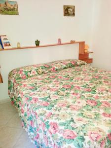 ネットゥーノにあるHome Sweet Seaのベッドルームに花柄のキルトが付いたベッド1台