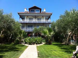 a large house with a balcony on top of a yard at Villa Di Costa in Nea Skioni