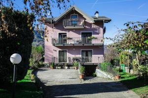 ein rosafarbenes Haus mit Balkon und Auffahrt in der Unterkunft Casa De Val in Calceranica al Lago