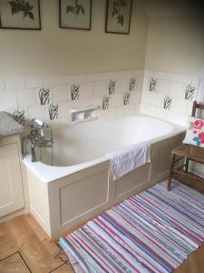 bañera blanca en una habitación con alfombra en Church Hill Farm en Lighthorne