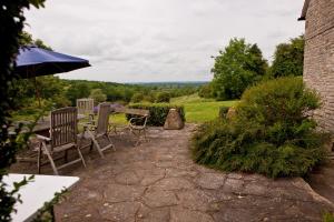 eine Terrasse mit 2 Stühlen, einem Tisch und einem Sonnenschirm in der Unterkunft Church Hill Farm in Lighthorne