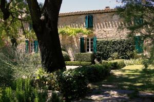 un antico edificio in pietra con finestre verdi e un albero di La Maison Du Village a Val-de-Dagne