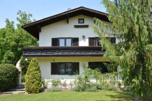 una casa blanca con ventanas negras y un árbol en Haus mit Garten, en Eugendorf