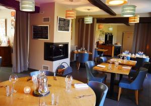 un restaurant avec des tables en bois et des chaises bleues dans l'établissement Logis - Auberge de l'Abbaye, à Thiron-Gardais