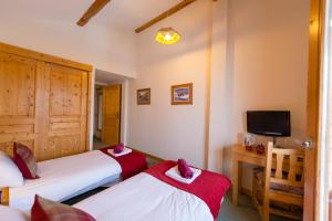2 Betten in einem Zimmer mit einem TV und einem Schreibtisch in der Unterkunft Chalet Coeur des Brévières by Chalet Chardons in Tignes
