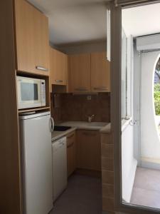 eine Küche mit einem weißen Kühlschrank und einer Mikrowelle in der Unterkunft studio parking 5 min de la plage in La Grande-Motte