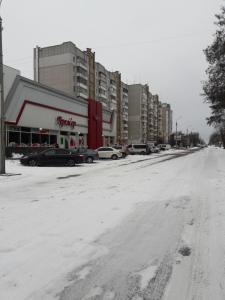 una calle nevada con coches estacionados frente a los edificios en Apartment Prem'yer, en Cherkasy