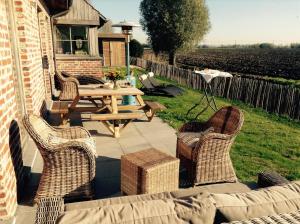une terrasse avec une table de pique-nique, des chaises et un champ dans l'établissement Lodela, à Lo-Reninge