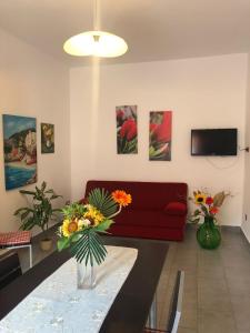 una sala de estar con sofá rojo y flores en una mesa en Casa Longo 2, en Castellammare del Golfo
