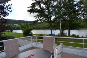 a balcony with a table and chairs and a view of a river at la terrasse du lac in Vielsalm