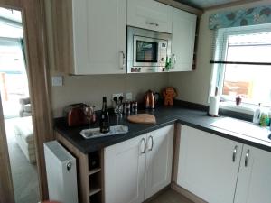 a kitchen with white cabinets and a counter top at 11 Burnside Lodge in Auchterarder