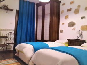 two beds in a bedroom with blue curtains at Golden Horn Guest House in Iskrets