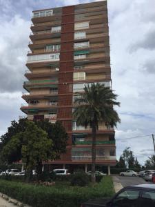 a tall building with a palm tree in front of it at First line Apartment in Alicante