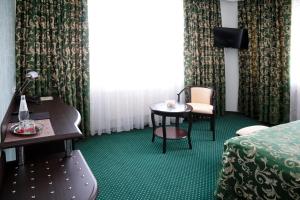 a hotel room with a bed and a table and chair at Отель Ринг Премиум in Volgograd