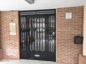 a black door with bars on a brick wall at First line Apartment in Alicante