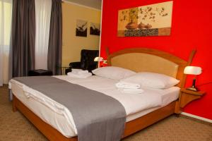 a bedroom with a large bed with a red wall at Aristo Hotel in Filderstadt