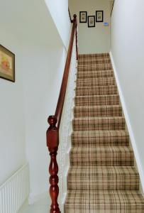 un tramo de escaleras con alfombra a cuadros en The Hollies, en Adare