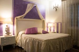 1 dormitorio con cama con dosel y pared morada en Agriturismo Campofiorito en Monsummano