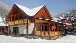 ein Blockhaus mit einem schneebedeckten Dach in der Unterkunft Casa Nova in Vişeu de Sus